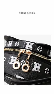Detailed close-up of dual golden zippers and cat floral print on black leather bag