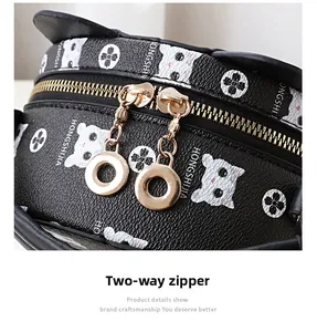 Close-up of golden dual zipper detail with circular pulls on a black monogram crossbody bag
