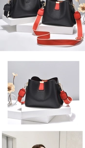 Detail of black lychee leather bucket bag with contrasting red wide shoulder strap