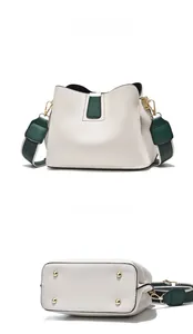 Detail view of white and green bucket bag with pebbled leather and protective base studs