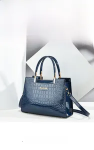 Close-up of navy blue crocodile-patterned handbag with polished finish and gold logo