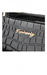 Close-up of black crocodile pattern leather bag with gold Danbaoly logo and zipper detail