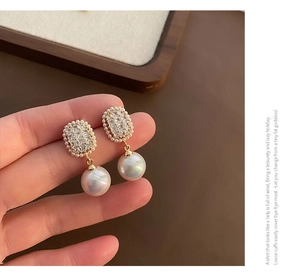Macro shot of luxury earrings with rectangular zircon studs and large radiant pearls