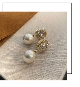 Macro shot of vintage pearl earrings with zircon inlay and golden floral detailing