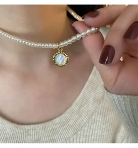 Details einer Vintage-Barock-Perlenkette mit goldenem Muschelanhänger am Hals getragen