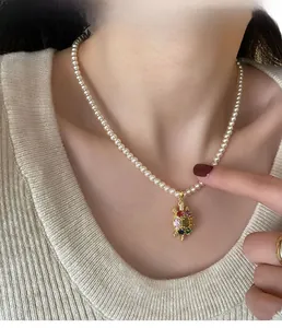 Gros plan sur un collier de perles avec pendentif tortue en zircons colorés porté
