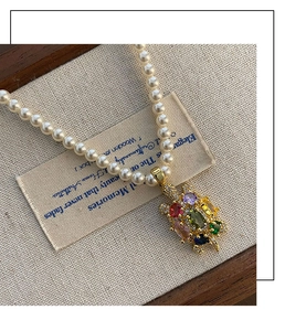 Détail d'un pendentif tortue en zircons colorés sur un collier de perles blanches