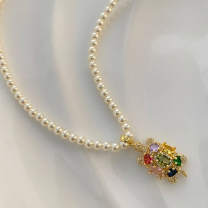 Collier de perles élégant avec pendentif tortue en zircons colorés sur soie blanche