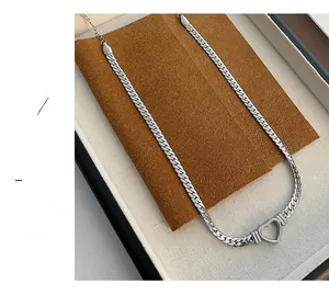 Détail d'un pendentif cœur creux argenté sur une grosse chaîne gourmette pour femme