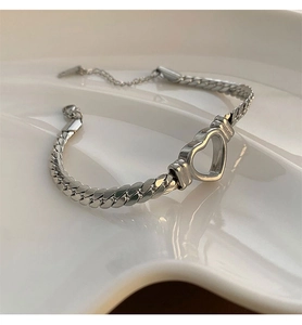 Détail du pendentif cœur évidé sur une chaîne plate argentée avec fermoir mousqueton
