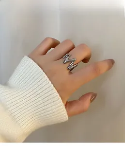 Close-up of a silver wave-shaped adjustable open ring with a mirror-polished finish