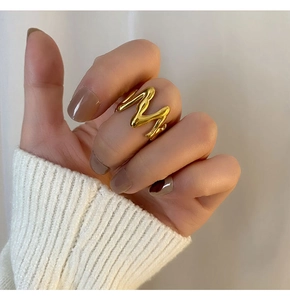Detailed view of an 18K gold plated stainless steel M-shaped ring worn on finger