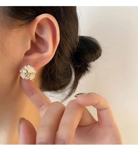 Detail eines Blumen-Ohrrings mit Perlen und Zirkon am Ohr einer Frau getragen