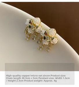 Macro detail of white camellia earring with zircon inlays and golden butterfly accent
