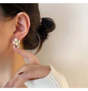 Detailed view of white camellia earring with zircon center on model's ear
