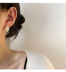 Detail of white camellia drop earrings with zircon accents on a female model