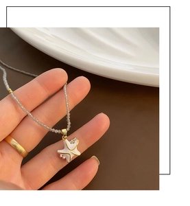 Gros plan d'un collier étoile de mer blanche avec bordure dorée et chaîne de perles