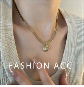 Detail of layered gold necklace with shell pendant and rhinestones on neck