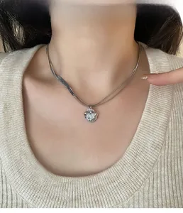 Close-up of a silver-toned shell pendant necklace with white pearl inlay on a model