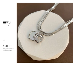 Macro detail of silver shell pendant with tiny zircons on flat snake bone chain