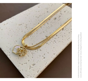 Close-up of double layer gold snake chain necklace with shell pendant and zircon details