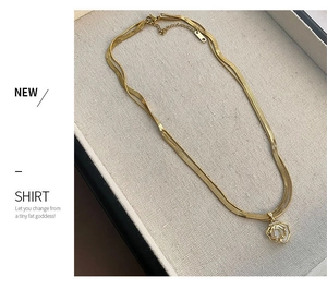Close-up of gold layered snake chain necklace with a fan-shaped shell pendant and diamonds