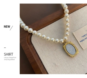 Gros plan d'un collier de perles avec pendentif rose doré sur bois et toile