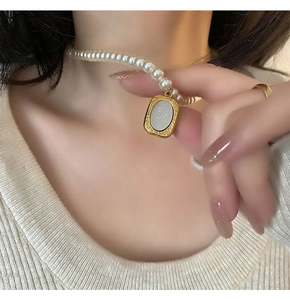 Détail d'un collier de perles avec pendentif rose doré sur fond en maille douce