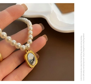 Gros plan d'un collier de perles vintage avec pendentif floral noir et cadre doré ciselé