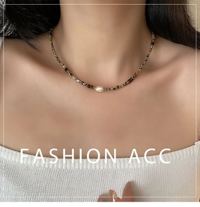 Detailed view of Baroque pearl necklace with tiger eye beads on a white knit sweater