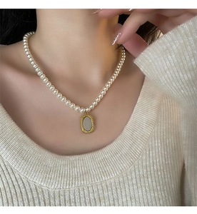 Détail d'un collier de perles avec pendentif fleur dorée vintage sur le cou