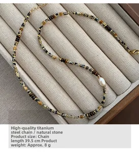 Detailed macro of baroque pearl and tiger eye stone necklace with gold titanium steel chain
