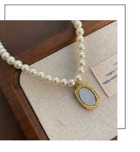 Détail d'un collier de perles vintage avec pendentif doré à relief de rose élégant