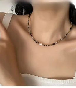 Close-up of baroque pearl necklace with brown tiger eye beads on model neck