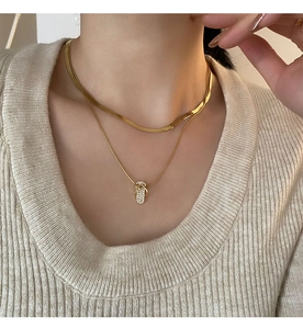 Detailed view of a gold double-layer necklace with a micro-paved crystal oval pendant