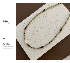 Macro view of baroque pearl and tiger eye stone beads on a vintage gold accented necklace