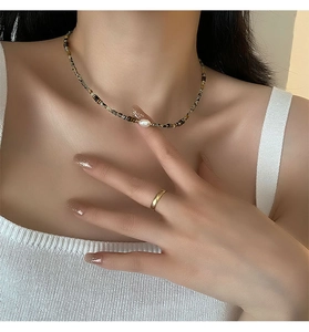 Detail of baroque pearl necklace with tiger eye beads and gold minimalist ring