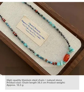 Dettaglio di collana etnica artigianale con pietra rossa e perline in titanio su lino