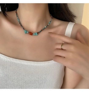 Dettaglio di una collana etnica con perle di turchese e pietre di agata su modella