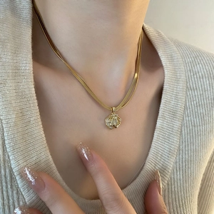 Gold layered necklace featuring a sleek snake chain and a sparkling shell pendant