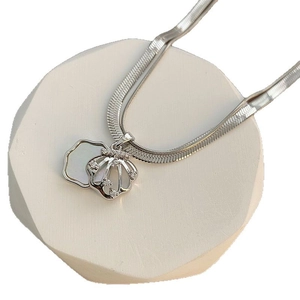 Silver double layer necklace with shell pendant and zircon stones on a white stone background