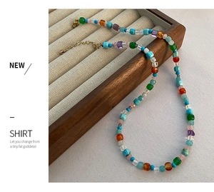 Vue macro d'un collier de perles colorées avec fermoir doré sur un plateau à bijoux en bois