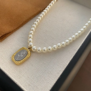 Collier de perles élégant avec pendentif rose dorée vintage sur une boîte à bijoux de luxe