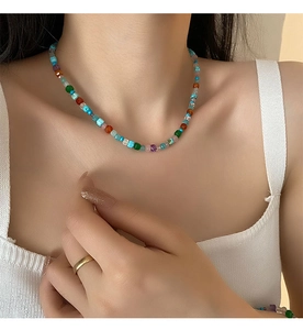 Détail d'un collier en pierres naturelles colorées avec une bague dorée minimaliste