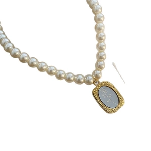 Collier de perles vintage avec pendentif rose rectangulaire doré et fond bleu