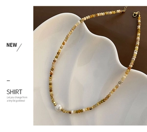 Detail of beaded necklace with natural brown stones, fresh water pearl and gold spacers