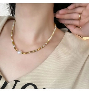 Detail of beaded necklace with natural stone and freshwater pearl on neck