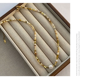 Detail of beaded necklace with natural stones, a baroque pearl and gold lobster clasp