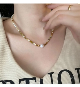 Detail of beaded necklace with natural stones and irregular freshwater pearl on model