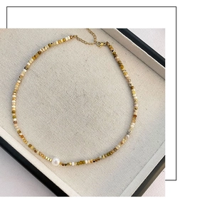 Detailed shot of bohemian beaded necklace with natural stones, pearl and gold clasp
